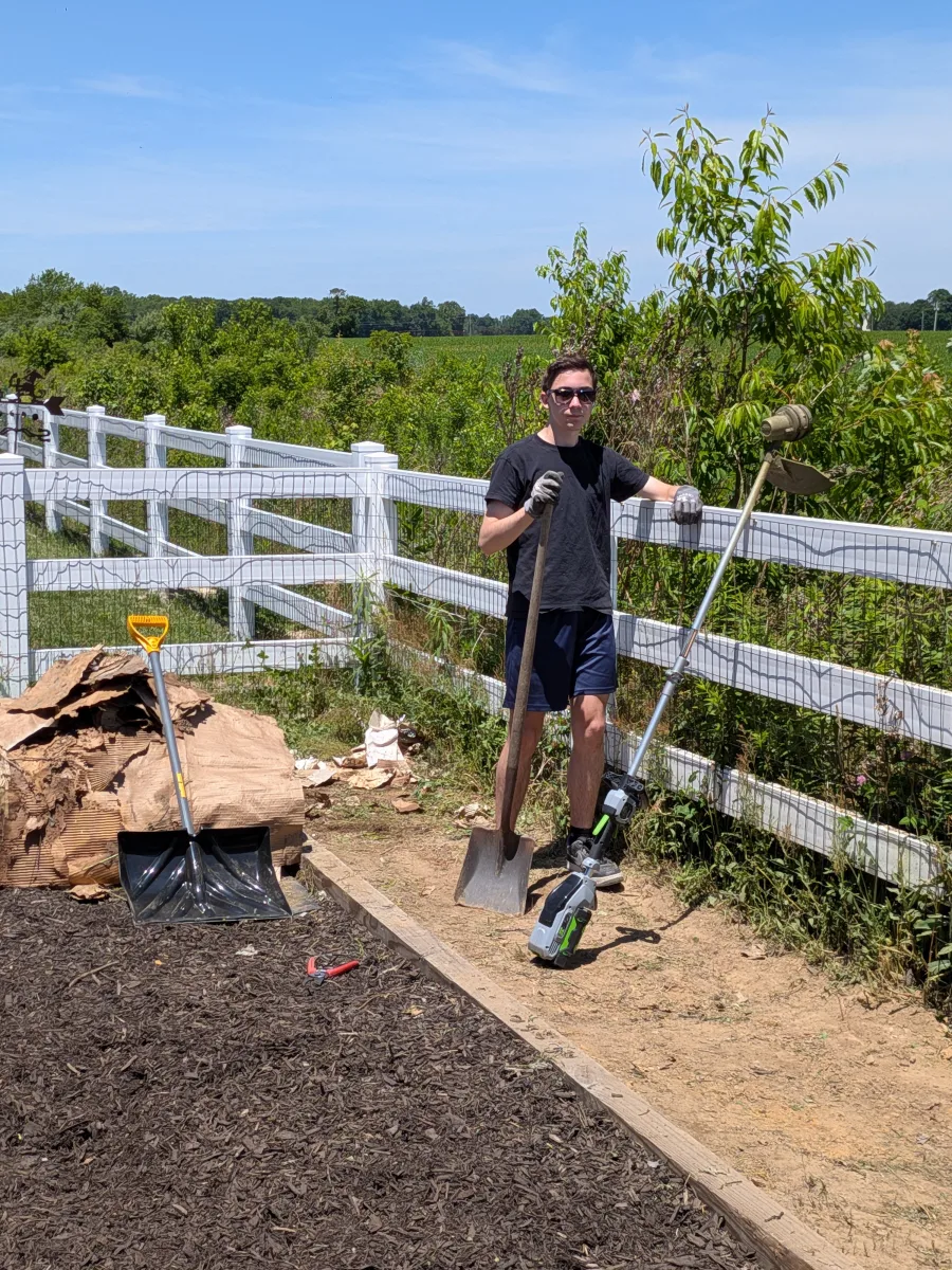 Gavin standing by yard tools in a neighborhood garden area.
